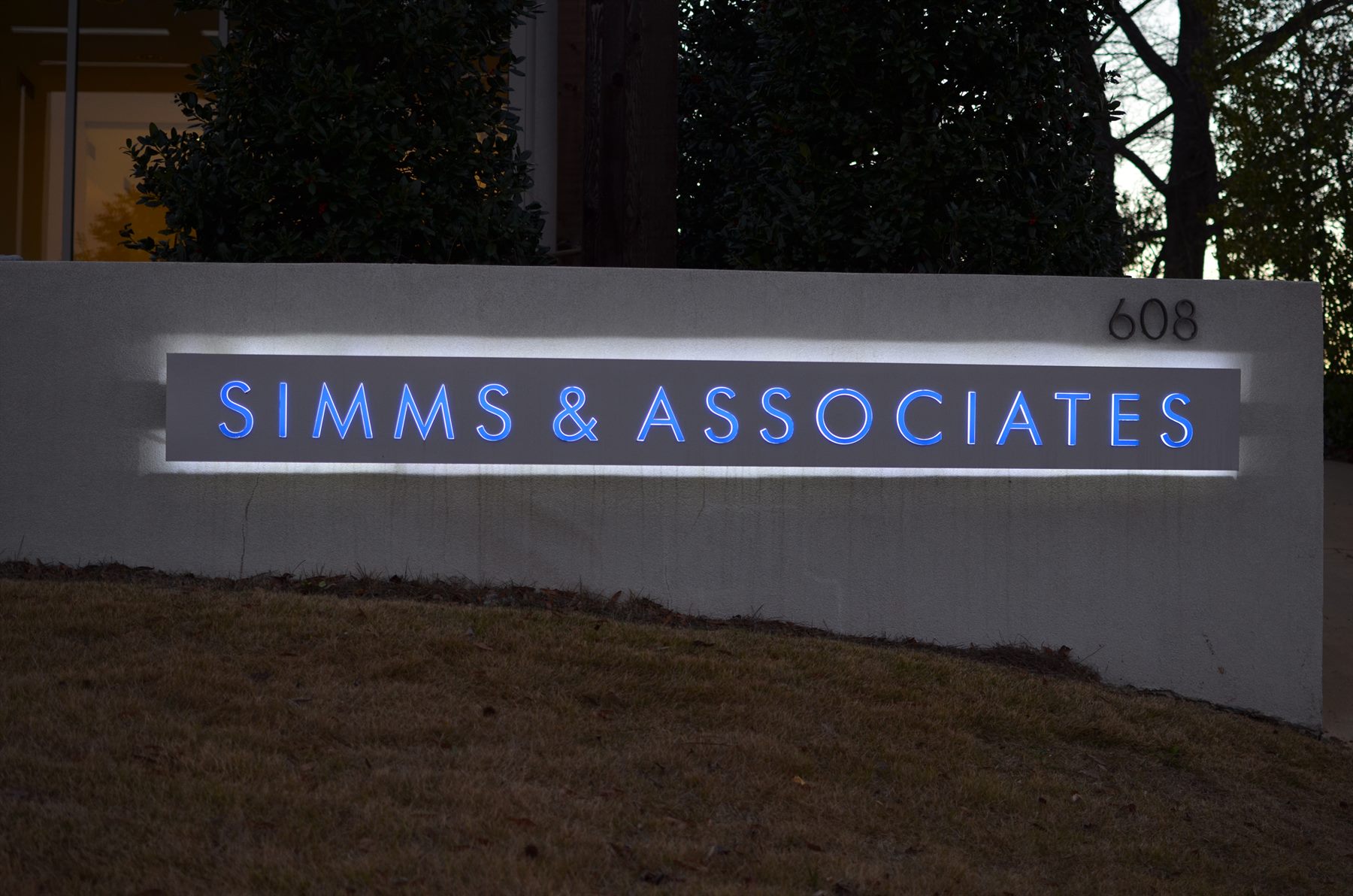 The Simms & Associates office sign, illuminated at dusk